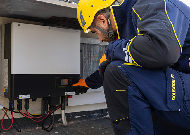 Tecnico Acrobatica con casco giallo e divisa installa un inverter fotovoltaico