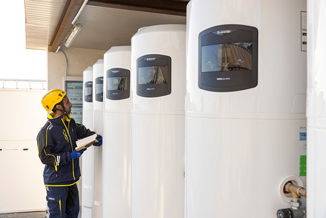 Tecnico controlla una fila di scaldacqua a pompa di calore ibridi